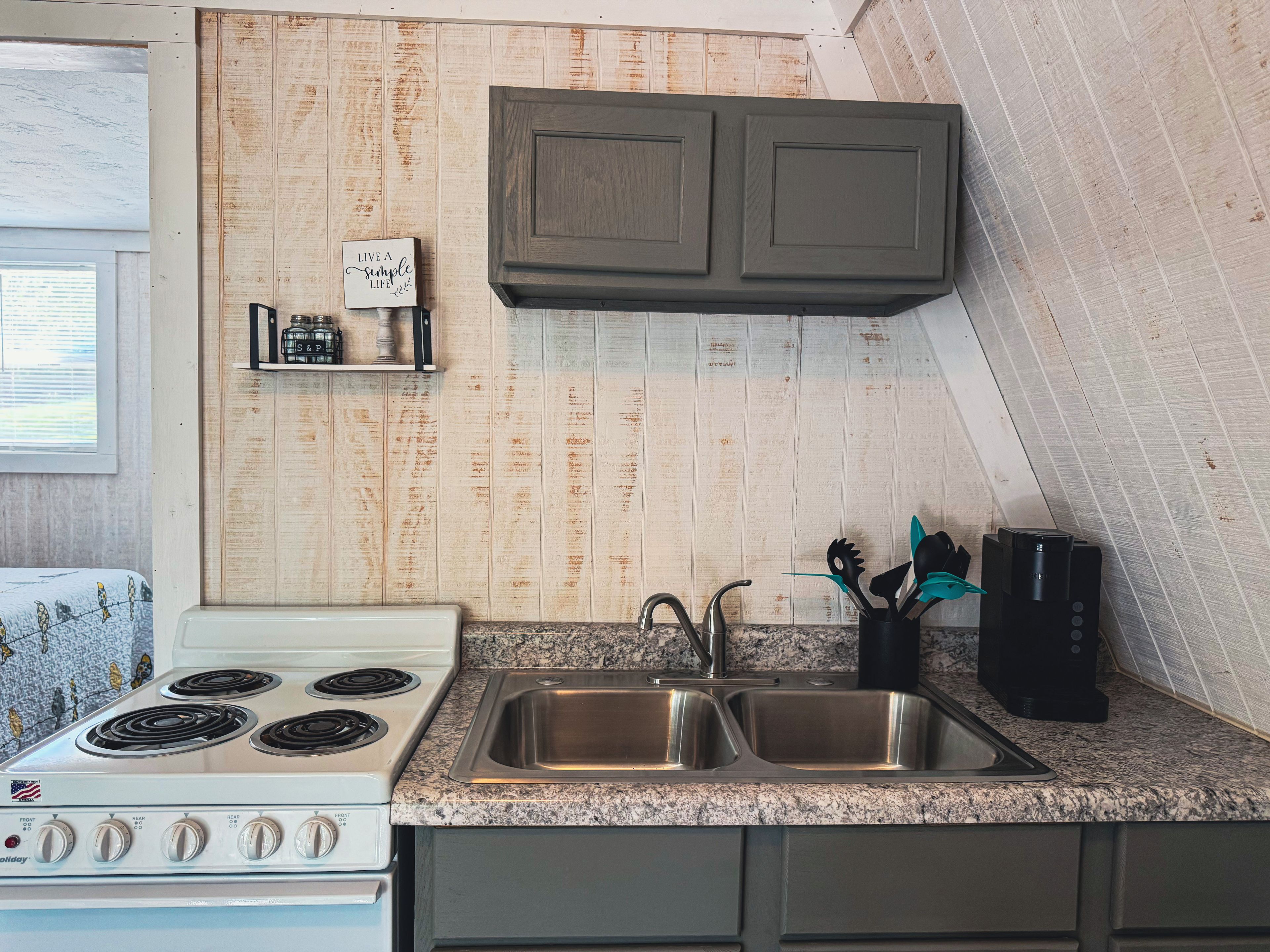 Una cocina con estufa blanca, pileta doble y muebles de madera.