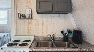 Una cocina con estufa blanca, pileta doble y muebles de madera.