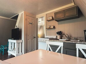 A compact kitchen with a stove, sink, and a television on a small table. - Table Rock Lake A-Frame Cabin | Black Oak Lodge 4 (Lampe)