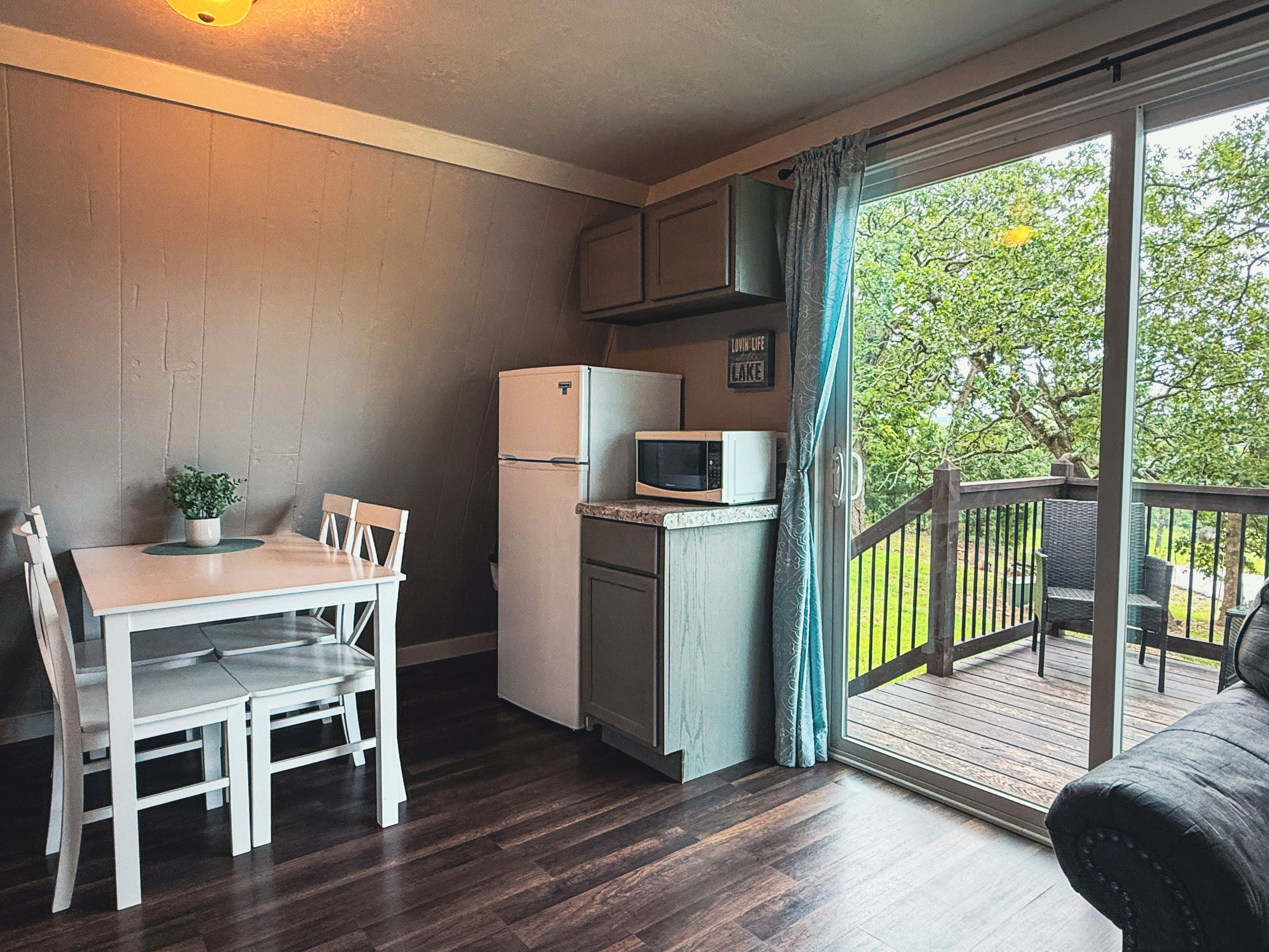 Cocina compacta con refrigerador, microondas y mesa de comedor con sillas.