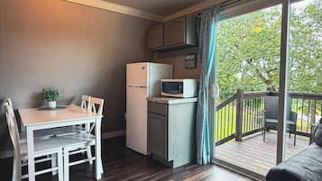 Cocina compacta con refrigerador, microondas y mesa de comedor con sillas.