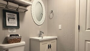 Een badkamer met toilet, wastafel, spiegel en een bord met een lijst.