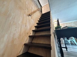 A wooden staircase with a handrail, leading to a landing with a potted plant and a table with chairs. - Table Rock Lake A-Frame Cabin | Black Oak Lodge 5 (Lampe)