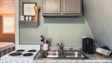 A kitchen with a white stove, two sinks, wooden cabinets, and a framed sign on the wall.