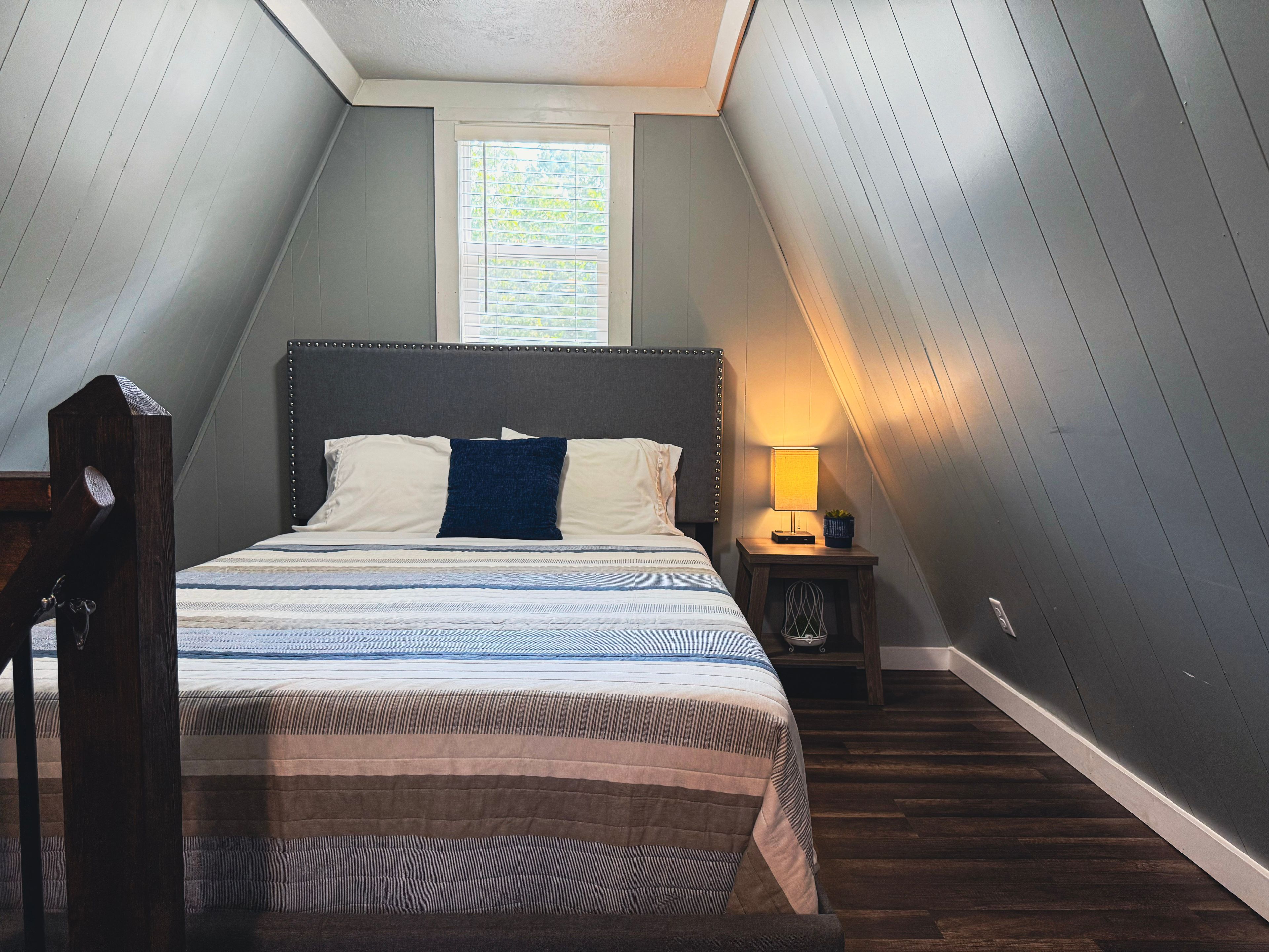 A bedroom with a bed, bedside lamp, and a window.
