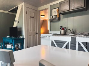 A compact kitchen with a stove, sink, and a dining area. - Table Rock Lake A-Frame Cabin | Black Oak Lodge 5 (Lampe)