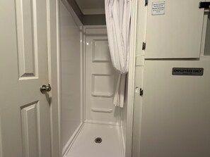 Un baño con ducha, una toalla colgada en la pared y un cartel que dice 'PERSONAL AUTORIZADO'.