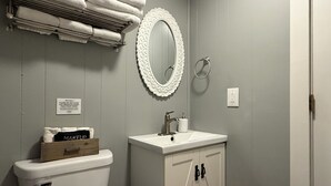 Un baño con inodoro, lavamanos y espejo con marco decorativo.
