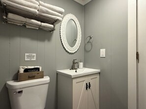 Casa de banho com sanita, lavatório e espelho com moldura decorada.