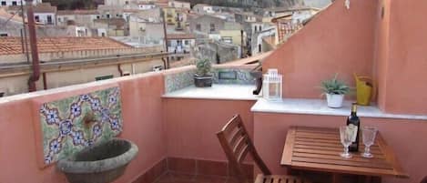 Un balcón con vistas a un pueblo, un lavabo, una mesa con sillas y una planta en maceta.