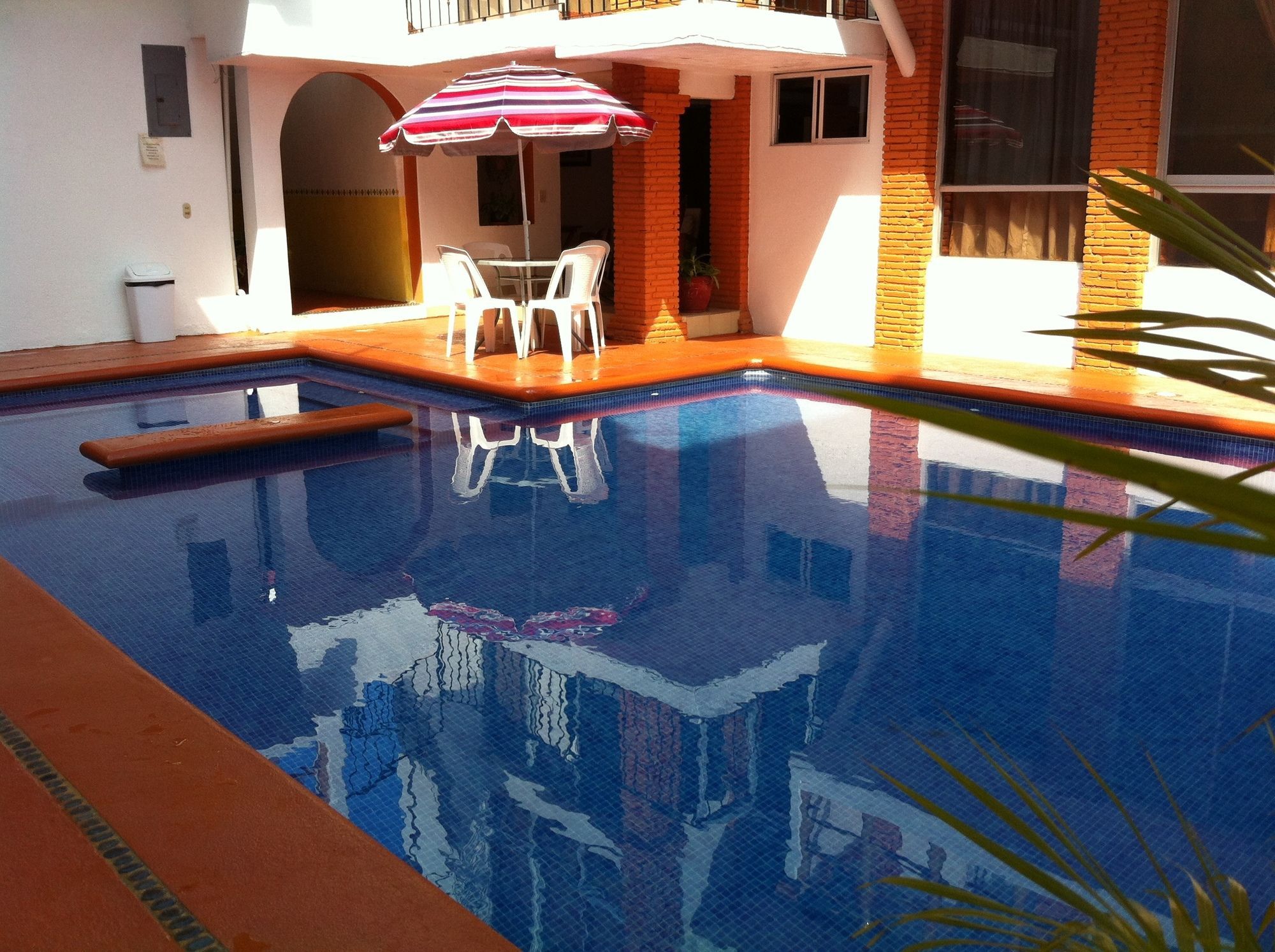 A swimming pool with a sunshade, a small table, and chairs.