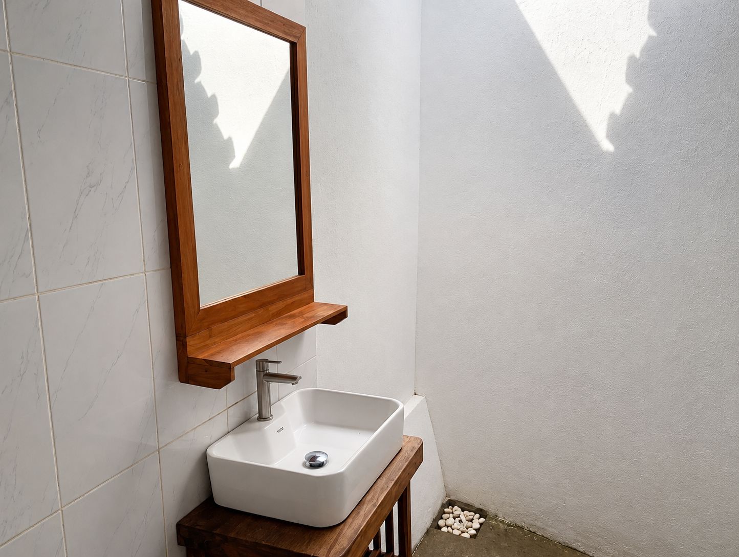 A bathroom with a white sink, wooden vanity, and a mirror with a wooden frame.