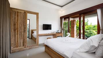 A bedroom with a bed, a desk, a television, and a large mirror.