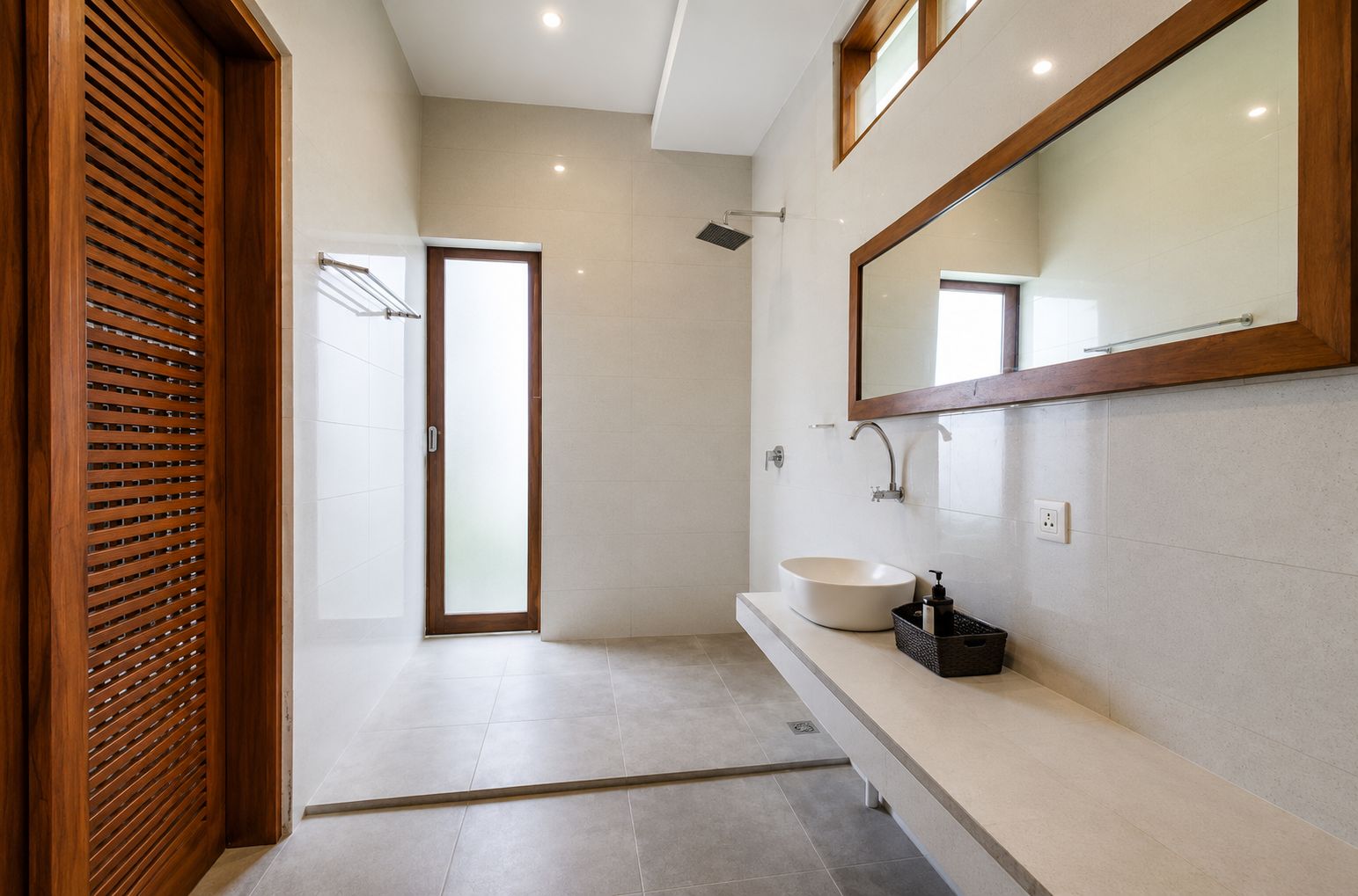 A modern bathroom with a large mirror, a round sink, and a shower.