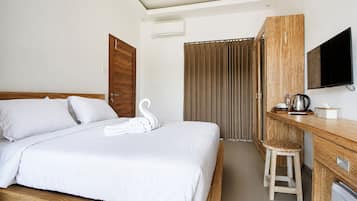A hotel room with a bed, a wooden desk, a television, and a shower area.