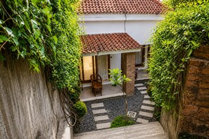 A courtyard with a tiled roof, a wooden chair, and a small plant. - Keramas Jungle House (Gianyar)