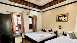 Habitación de hotel con dos camas, un escritorio, un armario y un ventilador de techo.