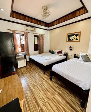 A hotel room with two beds, a desk, a wardrobe, and a ceiling fan. - Singharat Guest House (Luang Prabang)