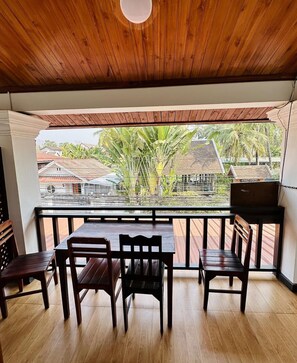 A wooden ceiling, a balcony with a view of houses and trees, and a table with chairs. - Singharat Guest House (Luang Prabang)