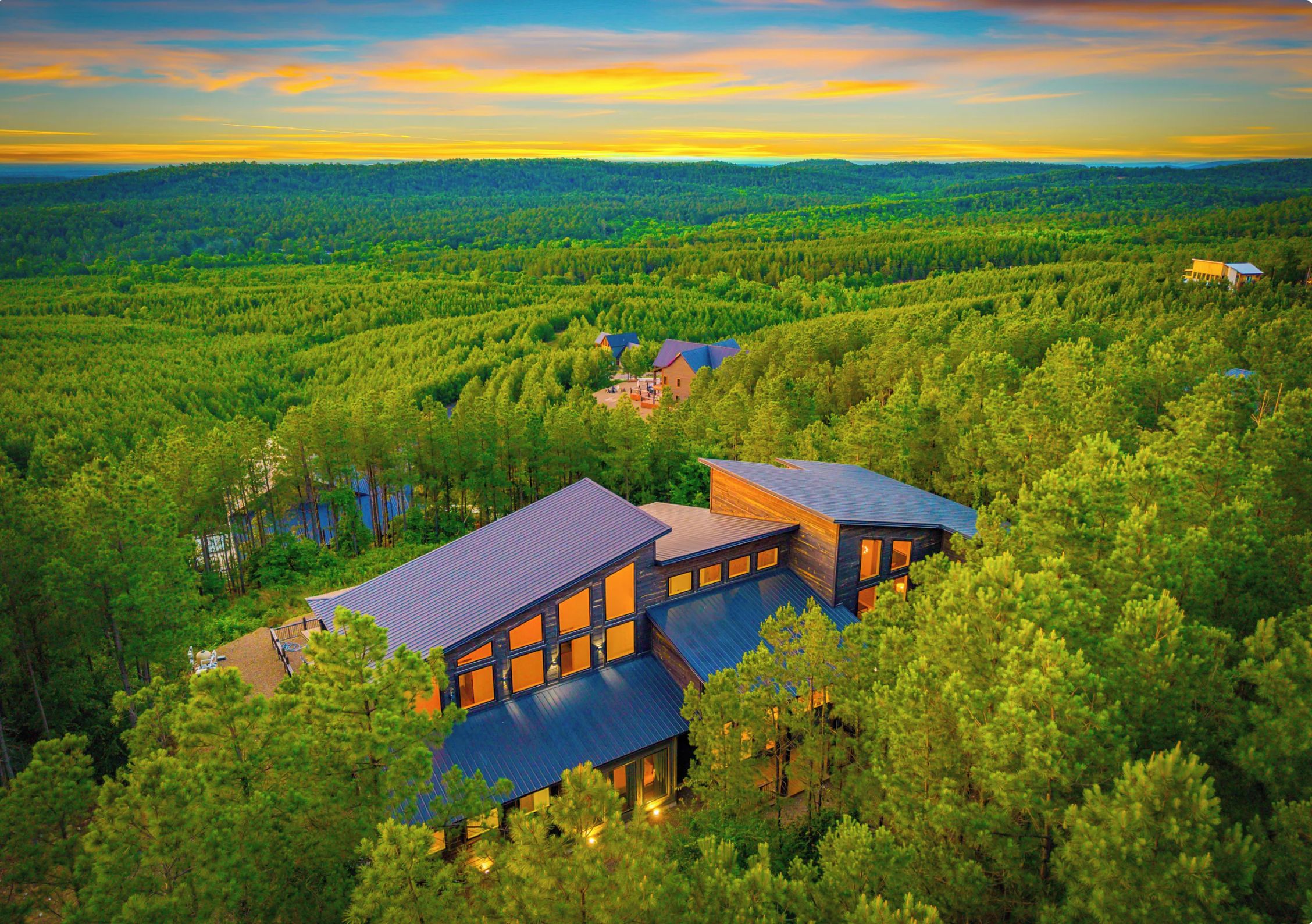 A modern house surrounded by dense forest, with a clear view of the landscape.