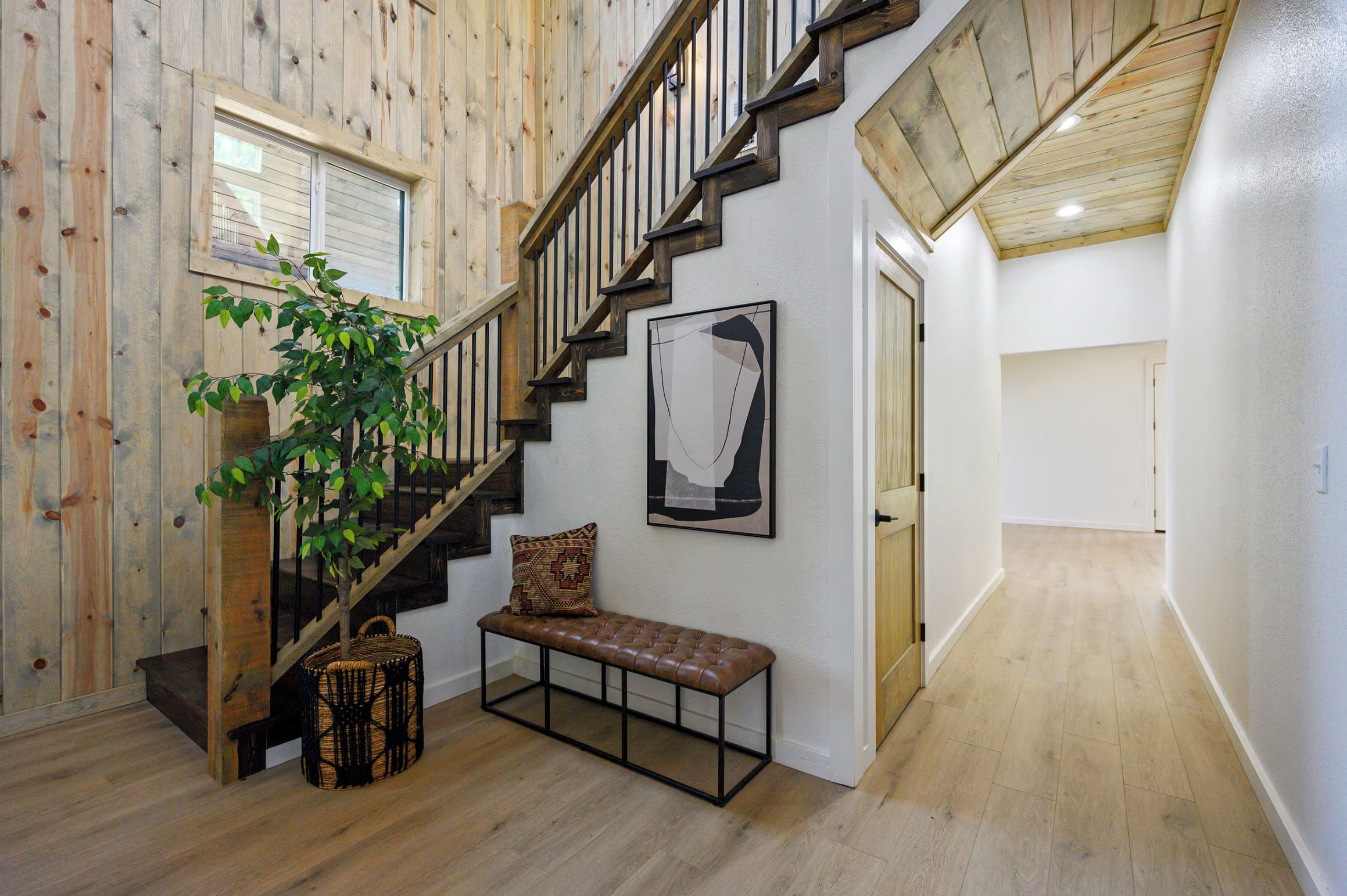 A wooden staircase with a bench and a plant, leading to a door.
