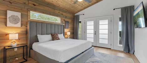 Un dormitorio con cama, mesita de noche, ventilador de techo y ventana.