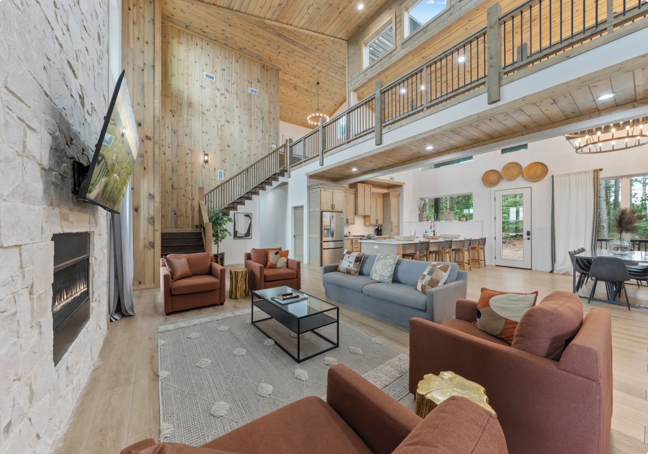 A spacious living area with a fireplace, sofas, a coffee table, and a kitchen in the background.