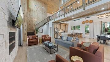 A spacious living area with a fireplace, sofas, a coffee table, and a kitchen in the background.