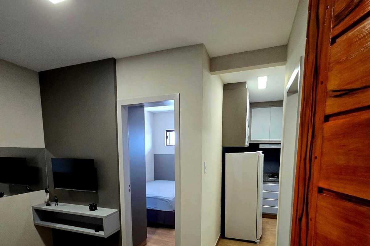 A compact living space with a kitchenette, a television, and a bed.