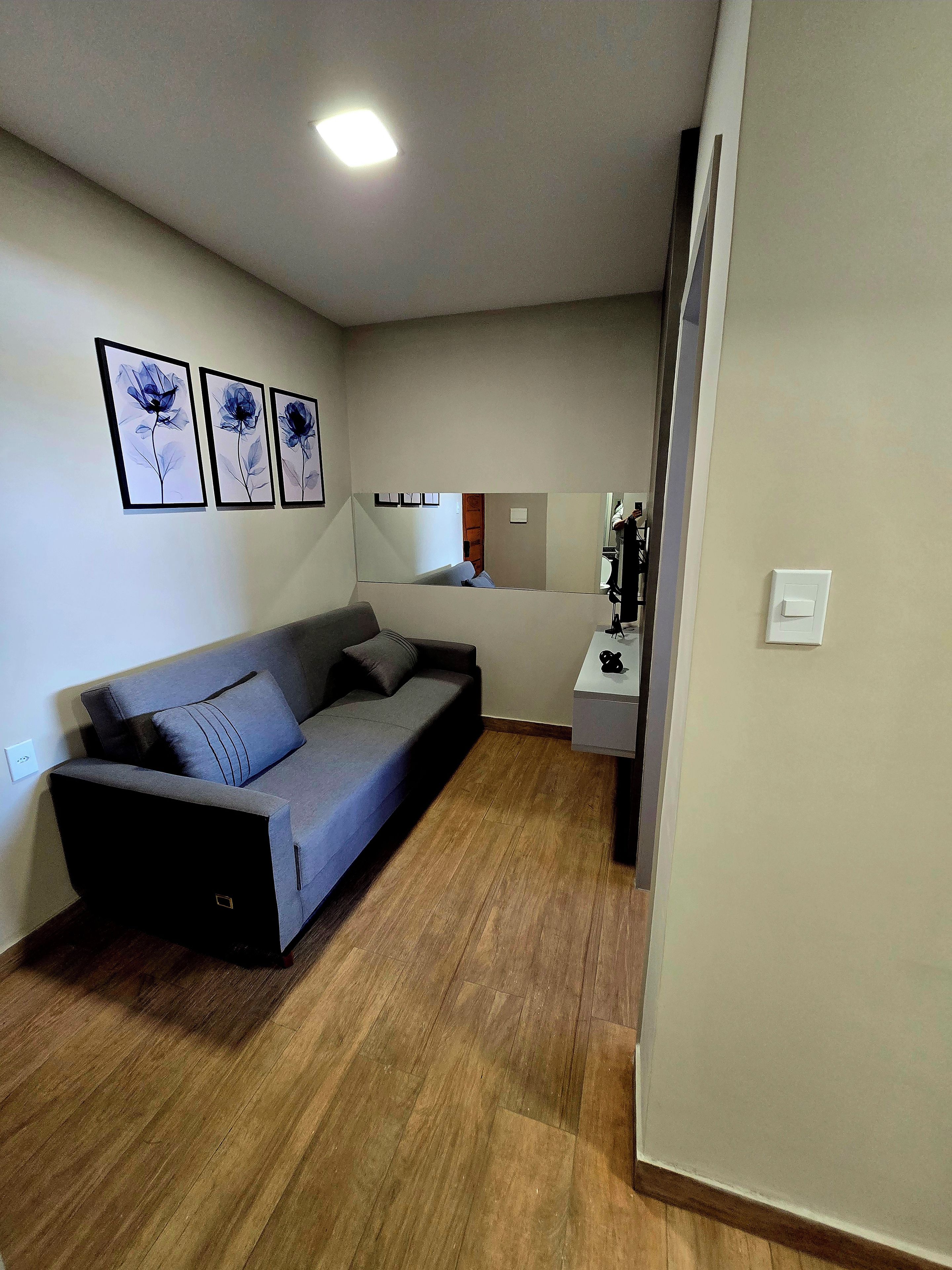 Uma sala de estar moderna com um sofá, uma TV de tela plana e obras de arte emolduradas na parede.