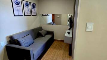 A compact living space with a sofa, a small table, and a mirror.