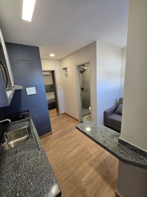 A modern kitchen with granite countertops, a built-in oven, and a small window. - Flat cidade do leite (Nossa Senhora da Glória)