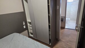 A bedroom with a bed, a wardrobe, and a door leading to a bathroom.