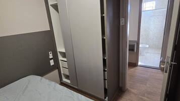 Une chambre à coucher avec un lit, une armoire et une salle de bain visible à travers une porte ouverte.