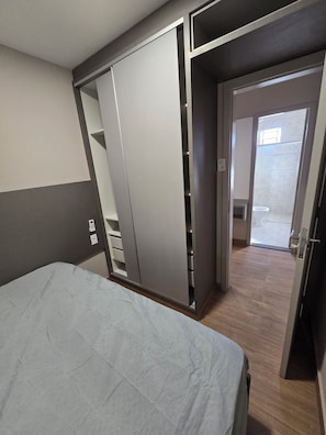 A bedroom with a bed, a wardrobe, and a door leading to a bathroom.
