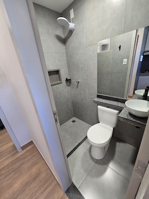 A modern bathroom with a shower, toilet, and sink.