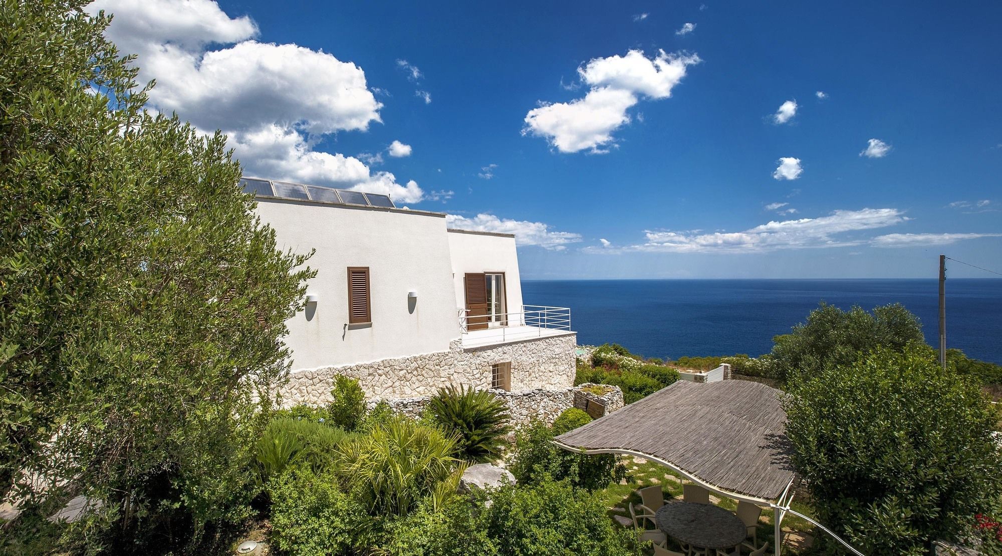 A coastal property with a white building, a stone base, and a view of the sea.