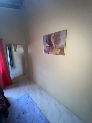 A room with a tiled floor, a painting on the wall, and a red curtain partially visible. - 🌴 New Harbour Haven | Spacious Family Retreat in Gated Community (Old Harbour)
