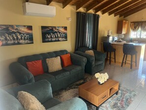 A living room with a grey sofa, a wooden coffee table, and artwork on the walls. - 🌴 New Harbour Haven | Spacious Family Retreat in Gated Community (Old Harbour)
