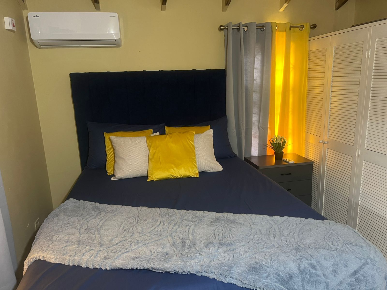 Un dormitorio con cama, mesita de noche, aire acondicionado y armario.
