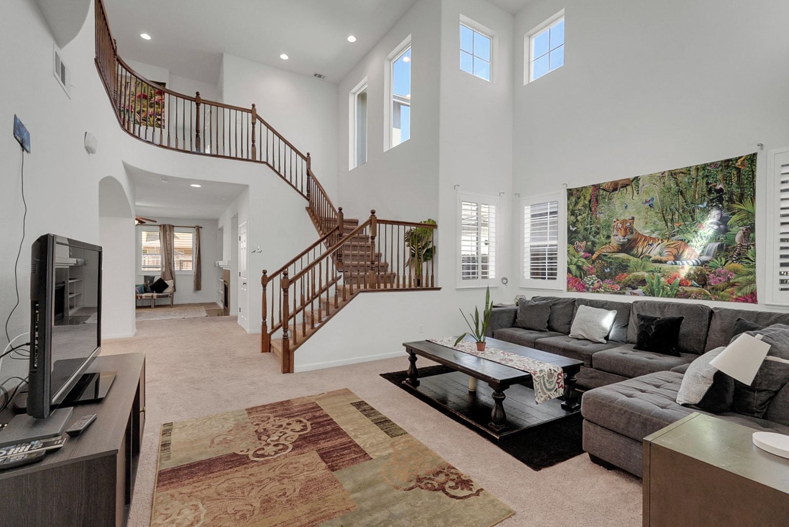 A spacious living area with a staircase, a large painting, and a television.