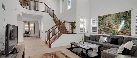 A spacious living area with a staircase, a large painting, and a television.