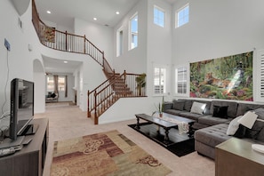 A spacious living area with a staircase, a large painting, and a television.