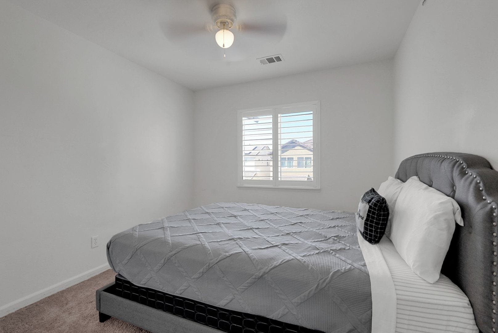 Un dormitorio con cama, ventana y ventilador de techo.