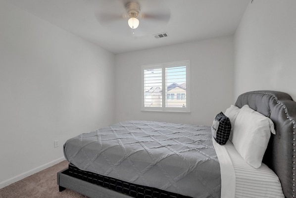 A bedroom with a bed, a window, and a ceiling fan.