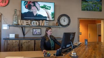 A reception desk with a television screen, a clock, and a welcome sign.