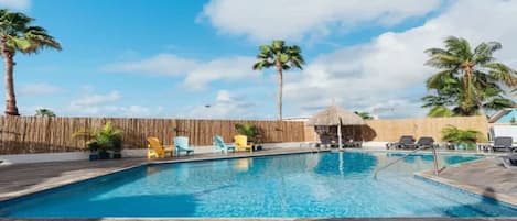 A swimming pool with lounge chairs and palm trees.