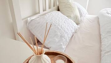 A neatly made bed with white bedding and a wooden headboard.