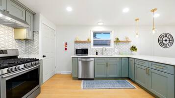 A modern kitchen with stainless steel appliances, light blue cabinets, and a patterned backsplash.