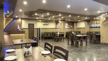 A restaurant with multiple dining tables and chairs, a marble floor, and a ceiling with recessed lighting.